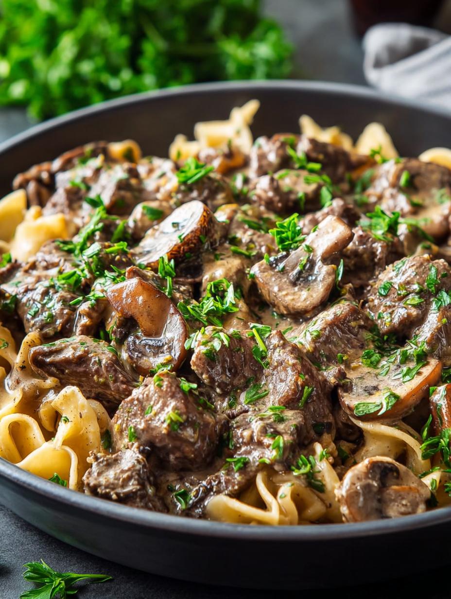 Amazing Beef Stroganoff served over egg noodles, garnished with fresh parsley, showcasing tender beef and creamy sauce - main visual representation